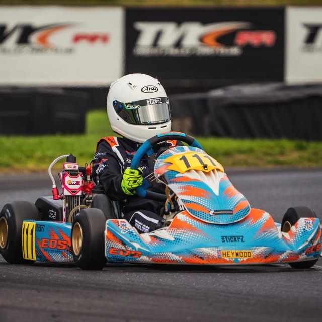 Felix driving his blue and orange racing kart with number 111 visible
